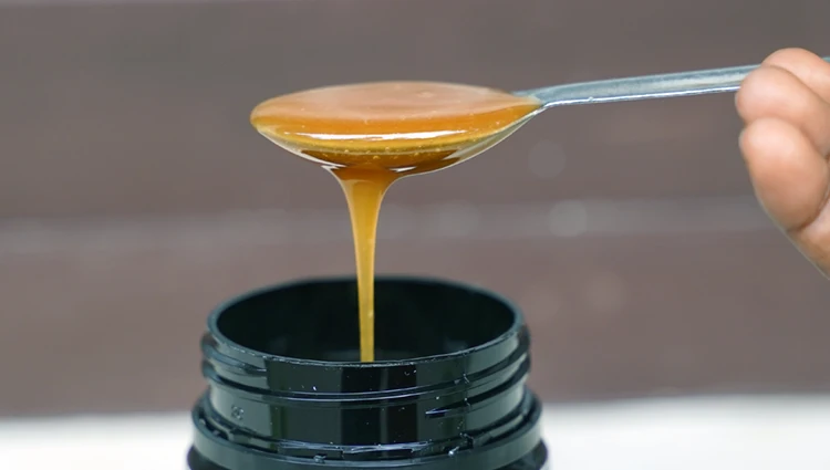 spoon lifting manuka honey from a jar